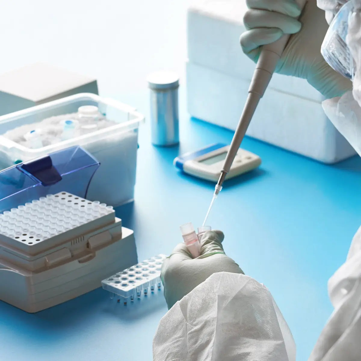 Scientist using syringe to gather liquids from vial