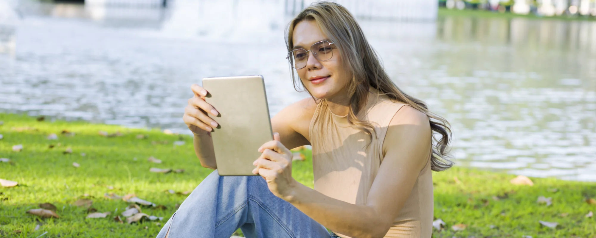 Transgender woman looking at CryoChoice Sperm preservation options on an ipad next to a lake.