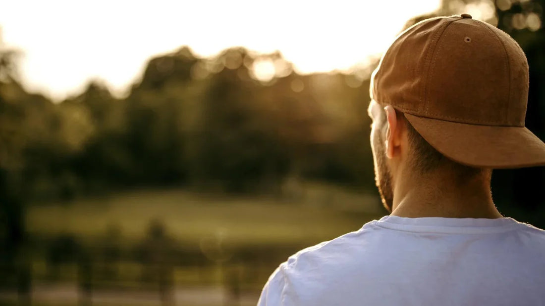 Man with backward baseball hat looking out across a field