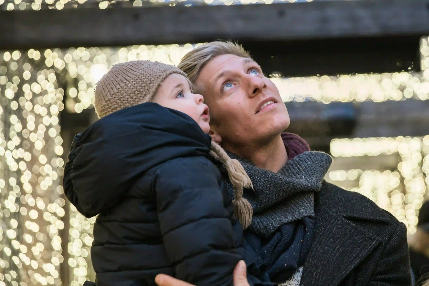 Father holding child looking up.