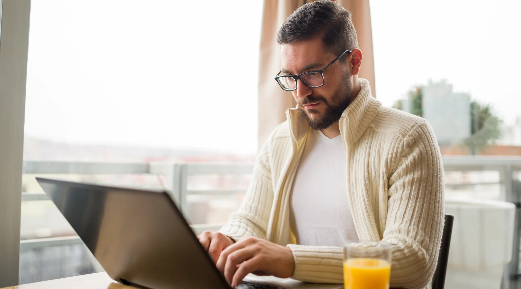 Man sitting at a table looking at a laptop computer